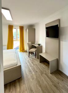 um quarto com uma cama, uma secretária e uma televisão em Reibersdorfer Hof em Parkstetten