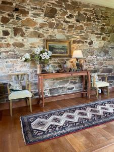 a room with a table and chairs and a stone wall at The Coach House on River and Park in Mudgee