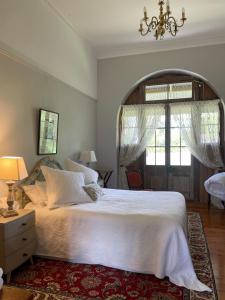 a bedroom with a large white bed and a chandelier at The Coach House on River and Park in Mudgee