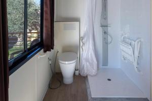 a small bathroom with a toilet and a window at Fornella Camping & Wellness family resort in San Felice del Benaco