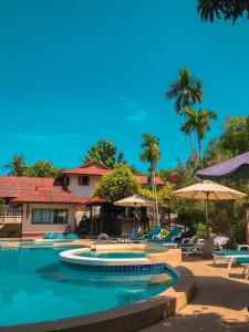a swimming pool with chairs and umbrellas in a resort at Tanouy Garden in Baan Khai