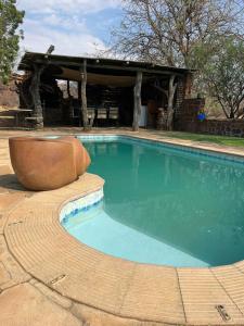 a swimming pool with a chair in front of a building at The Farmhouse in Okahandja
