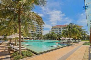 a swimming pool with palm trees and a building at Emblem Sea 3 bedroom villas in Danang