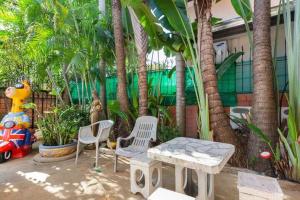 d'une terrasse avec des chaises, une table et des palmiers. dans l'établissement MADEE VILLA - PATTAYA HOLIDAY HOUSE WALKING STREET 6 bedrooms, à Pattaya (sud)