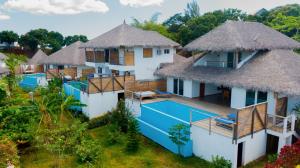 - une vue aérienne sur un complexe doté d'une piscine et d'un toit de chaume dans l'établissement Tiako Villas, à Ambondrona