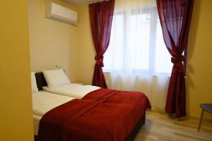 a bedroom with a bed and a window with red curtains at Hotel Leda in Sofia