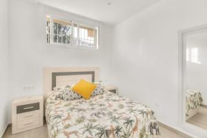 a white bedroom with a bed with a yellow pillow at MILLION APARTAMENT in Málaga