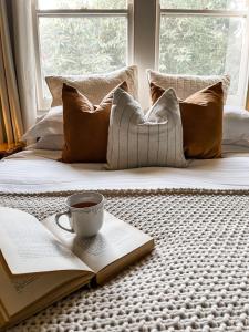 a book and a cup of coffee on a bed at Woolrich Historic Garden Accommodation in Olinda
