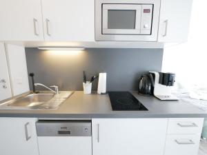 a white kitchen with a sink and a microwave at Zentral, modern, gemütlich mit Balkon & Parkplatz in Paderborn