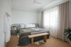 a bedroom with a bed and a table and a window at Motel Molly - Boutique Hotel Mollymook in Mollymook