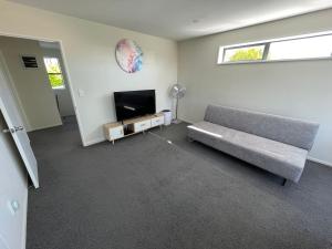 salon z kanapą i telewizorem z płaskim ekranem w obiekcie Quiet & New - Planted & Characteristic - 7Vhouse w mieście Christchurch