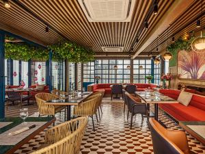 a restaurant with tables and couches and plants at Mytt Hotel Pattaya in Pattaya Central