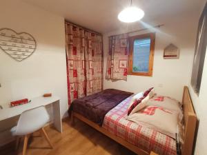um quarto com uma cama, uma secretária e uma janela em Appartement avec terrasse et parking Privé em Aigueblanche