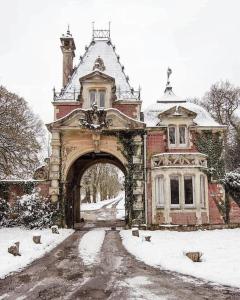 un antiguo edificio con un arco en la nieve en Historic 2 bed gatehouse in private parkland en Brockenhurst