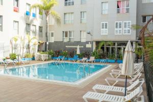 una piscina con tumbonas y un hotel en Home2Book Ático Blue Beach, Pool&Terrace, en Sardina