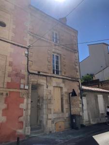 - un vieux bâtiment en pierre avec une porte en bois dans une rue dans l'établissement Le Bjorn - T1 chaleureux refait à neuf - Centre, à Niort