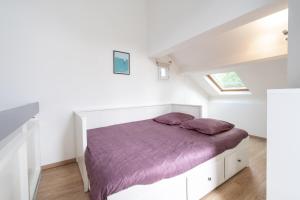 biała sypialnia z łóżkiem z fioletową pościelą w obiekcie Ty Treustel w mieście Combrit