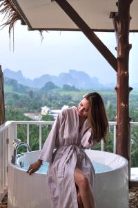 a woman in a robe sitting in a bath tub at Baan Phuvara Retreat - Romantic Jacuzzi Mountain View Villas in Ao Nang Beach