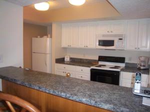 eine Küche mit weißen Schränken und einem weißen Kühlschrank in der Unterkunft Sandcastle Village II, a VRI resort in New Bern