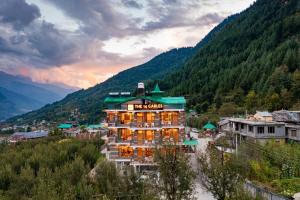 a hotel in a valley with mountains in the background at The 14 Gables, A Boutique Stay in Manāli