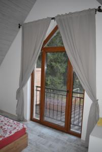 a bedroom with a large glass door with a balcony at cabana din padure in Finiş