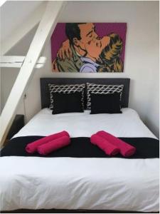 a bedroom with a bed with pink pillows and a painting at The pop-art luxury suite in Charleroi