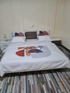 uma cama com uma colcha branca com uma fotografia em The FFG House - Appartements meublés Douala Cite des palmiers, Bonamoussadi em Douala