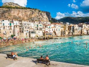 a group of people in the water at a beach at Carbonari Holiday House in Cefalù