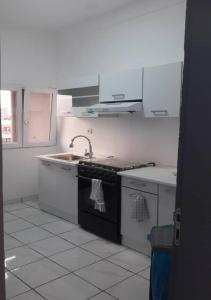 a kitchen with white cabinets and a black stove top oven at The FFG House - Appartements meublés Douala Cite des palmiers, Bonamoussadi in Douala