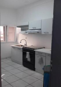a kitchen with white cabinets and a black stove top oven at The FFG House - Appartements meublés Douala Cite des palmiers, Bonamoussadi in Douala +10 photos
