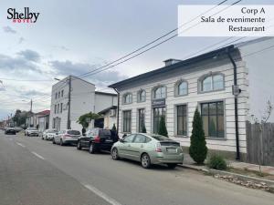 a street with cars parked in front of a building at Hotel Sinner's Shelby in Corabia