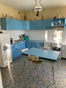 uma cozinha com armários azuis e uma mesa e cadeiras azuis em Location maison à Chadron : Haute Loire 
