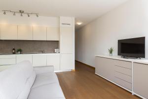 un soggiorno bianco con divano bianco e TV di Roggia 16 by Quokka 360 - central flat with balcony a Viganello
