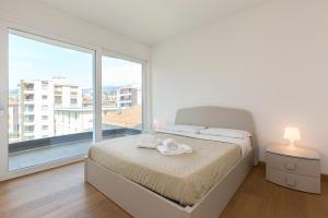 una camera bianca con un letto e una grande finestra di Roggia 16 by Quokka 360 - central flat with balcony a Viganello