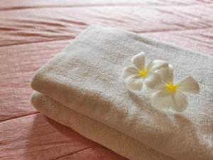 a towel with a white flower on a bed at TAVEE Guesthouse in Bangkok