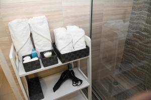 a bathroom shelf with towels and a glass shower at Lovely luxury apartment in Serres