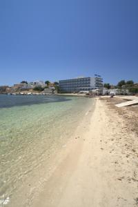 Hotel Argos Ibiza في تالامانكا: شاطئ رملي مع مبنى في الخلفية