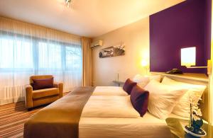 una habitación de hotel con una cama grande y una silla en Leonardo Inn Hotel Hamburg Airport, en Hamburgo