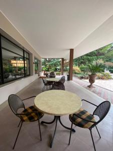 un patio con 2 mesas, sillas y ventanas en Hotel Rey's, en Montegrotto Terme