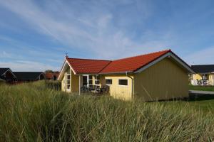 een geel huis met een rood dak in een veld bij Resort 2 Ferienhaus Typ D 130 in Großenbrode