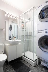 a white bathroom with a washing machine and a sink at The Golden Lion Street Getaway in Trondheim