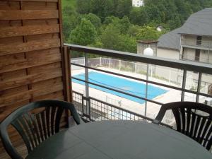 a balcony with a table and chairs and a swimming pool at STUDIO AVEC BALCON in Luz-Saint-Sauveur