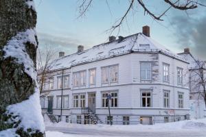 a large white building with snow on the ground at The Golden Lion Street Getaway in Trondheim