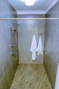 ein Bad mit Dusche und weißen Handtüchern an der Wand in der Unterkunft Nature Kigali in Kigali