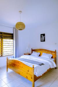 a large wooden bed in a white room with a window at Nature Kigali in Kigali
