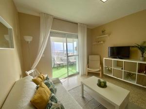 - un salon avec un canapé, une table et une fenêtre dans l'établissement Azvalia - Valdelagrana beach experience Piscina y parking gratis, à El Puerto de Santa María