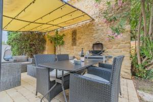 una mesa y sillas bajo una sombrilla en un patio en Mazet Magnan, Rustic Luxury in Provence, en Piolenc