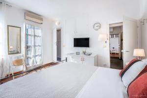 Un dormitorio blanco con una cama grande y un televisor. en Wine Apartments Florence Prugnolo, en Florencia
