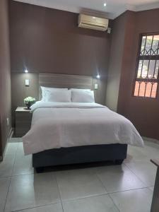 a bedroom with a large bed and a window at Franque Lodge in Durban