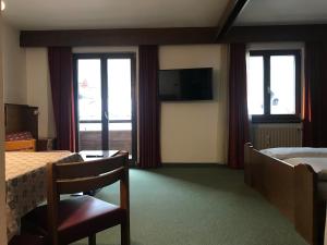 a hotel room with a bed and a tv and windows at Niki Appartments in San Candido